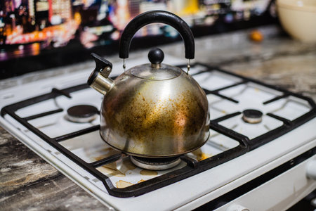 Dirty kettle stained with grease stands on a dirty kitchen stove