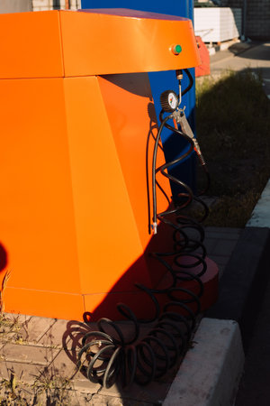 Vibrant orange air pump station for tire inflation with a pressure gauge and black hose.