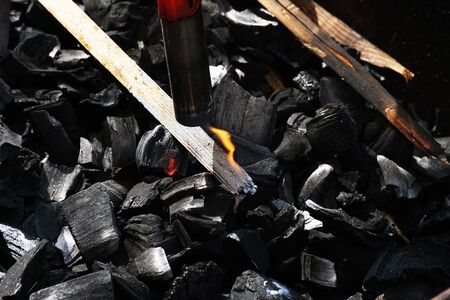 A man kindles charcoal in a barbecueの写真素材