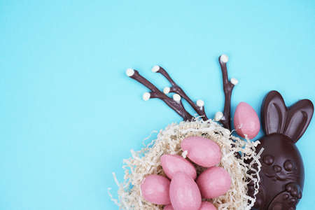 Beautiful Easter composition with Easter cake, chocolate eggs and a hare on a colored background.の写真素材