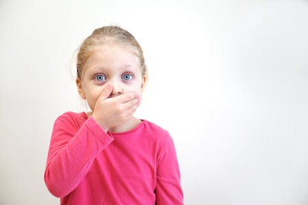 A cheerful little girl attracts attention with her emotions. Pointing with a finger, showing,...