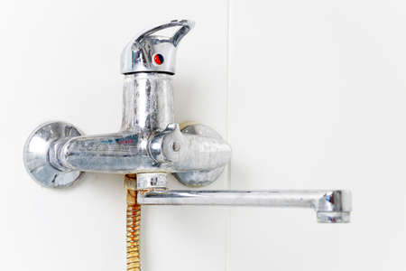 The faucet, mixer and hose in the bathroom are rusty, dirty, calcined with limescale. close-up. side view.の写真素材