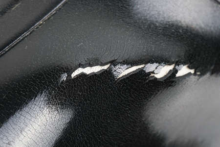An old rubber boot with a hole and cracks in the rubber. The quality of the shoes. Shoe repair. The texture of the structure of cracked rubber. Hole in the bootの写真素材