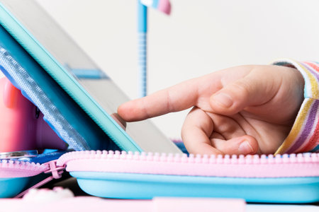 Childrens hand presses on the tablet screen. Finger on the tablet. Close-up gadget. Side view. Modern technology and home educationの写真素材