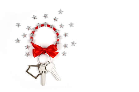 Keychain with keys on an isolated white background. Keychain - house, stars, red bow, 2 new keys. Keys as a gift. Beautiful background for buying real estateの写真素材
