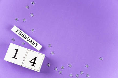 Valentines Day purple, lilac trendy background perpetual calendar white block with the date February 14, a scattering of silver stars. Copy space, flatlay.の写真素材