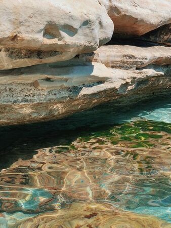 Sea water under the rock. Sea water washes the stones. Glare from water on rocksの写真素材