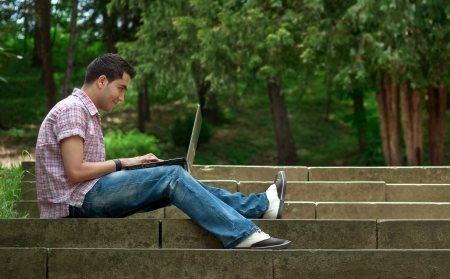 Young men sitting on stairway and using lap-topの写真素材
