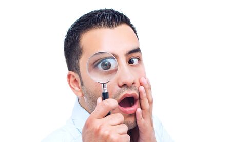 Young amazed man looking through magnifer, isolated on white background