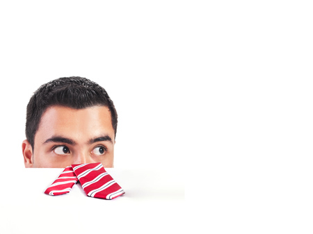 Shocked man peeking behind a blank white deskの写真素材