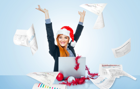 Happy christmas business woman celebrate successful year, papers or documents around in officeの写真素材