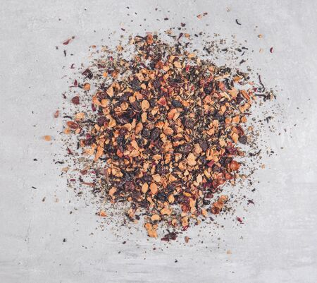 Heap of mix fruit tea and dried flowers on gray table. Pile mixture herbal floral fruit tea with petals. Tea backgroundの写真素材