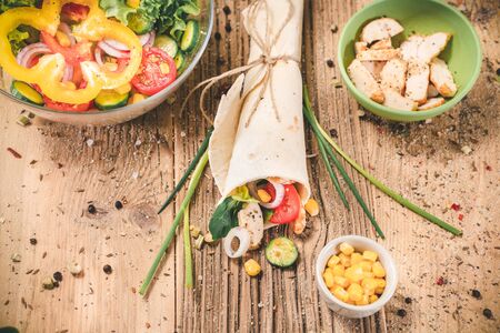 Homemade tortillas wraps with chicken and vegetables on wooden tableの写真素材