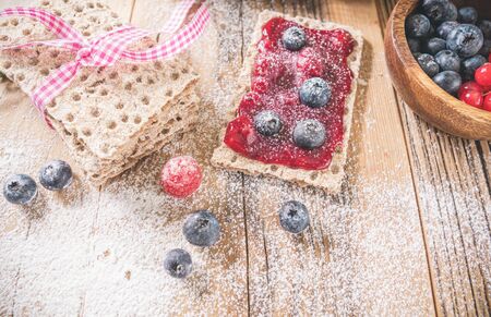 Decorated sweet breakfast with berries and toast over wooden table. Tasty healthy food 