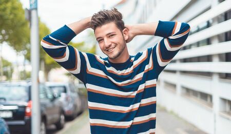 Smiling beautiful young man with modern hairstyle and expression on the face walking through street, outdoor - outsideの写真素材