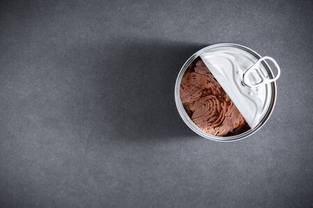 Open tin can with tuna fish, view or above on dark gray black background