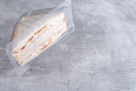 Sandwich in a transparent plastic box or nylon bag to go on gray backgroundの写真素材