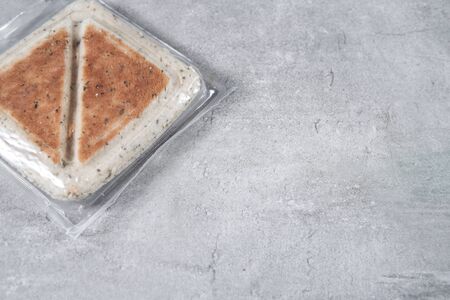 Sandwich in a transparent plastic box or nylon bag to go on gray background. Copy space