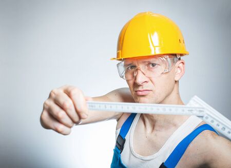 Closeup builder measuring something with folding rule, isolated on gray background, close-up studio shotの写真素材