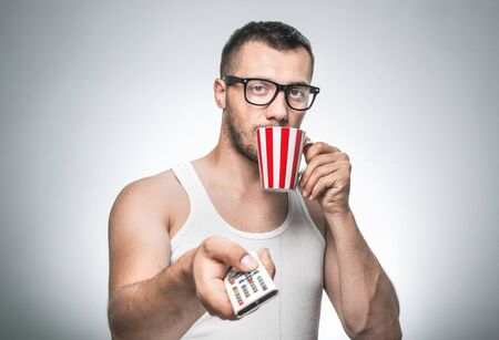 Man with cup coffee and remote control leisure and watching TV.
No stress, isolated on grayの写真素材