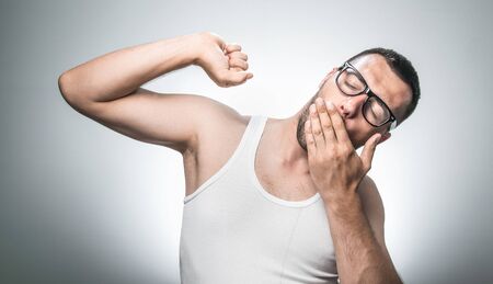 Man waking and yawn, isolated on gray background, studio shot.
Funny drowsy guy with hand - fingers in front of their mouthの写真素材