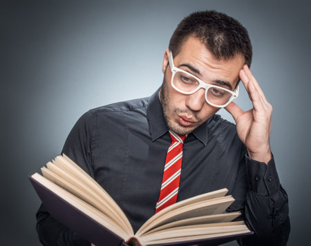 Worried professor or college student reading book, isolated on gray background, studio shotの写真素材