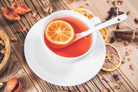 Cup of fruit tea with dry orange and cinnamon on wooden tableの写真素材