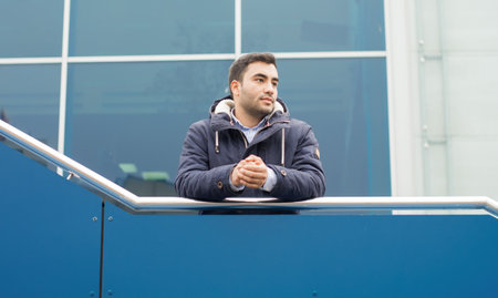 Casula young man on terrace looking to side. Gorgeous turk man in warmly jacket, outdoors - outside