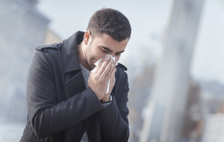 Man blowing his nose on street. Outdoorsの写真素材