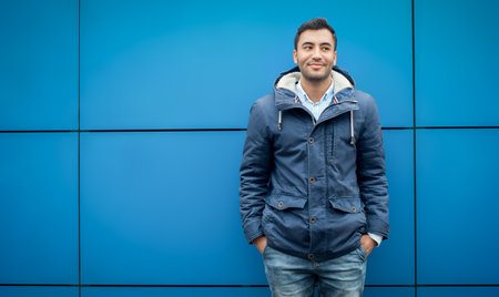 Young casual man standing in front of blue wall and looking to side, copyspace, outside - outdoorsの写真素材