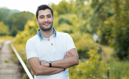 Portrait of a young smile man with crossed arms. Close up of a gorgeous guy, outdoorsの写真素材