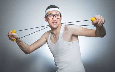 Loony skinny man exercise with expander doing fitness - training, isolated on gray white background