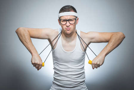 Strength skinny man exercise with expander doing fitness - training, isolated on gray white...