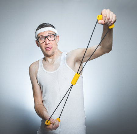 Loony skinny man exercise with expander doing fitness - training, isolated on gray white background