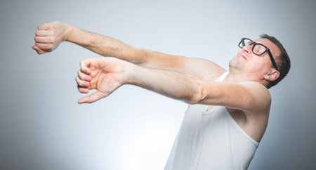 Man waking in morning, guy wearing undershirt and stretching their arms against white gray backgroundの写真素材