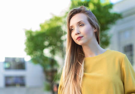Portrait of young attractive girl looking to side. Close up of beautiful woman, outdoor with blured...