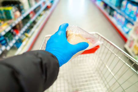 Buying supplies at nutrition during virus. Close up hand with product in supermarketの写真素材