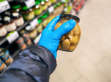 Buying supplies at nutrition during virus. Close up hand with product in supermarketの写真素材