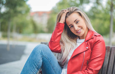 Smiling girl, looks to camera. Young happy woman model posing against blurred bokeh background. Outdoors - outsideの写真素材