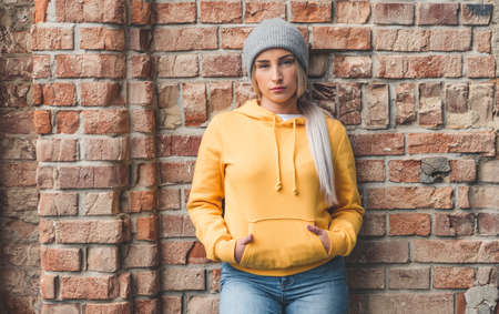 Trendy girl wears beanie while posing against bricks wall. Half-length of young cute woman. Outdoors - outsideの写真素材