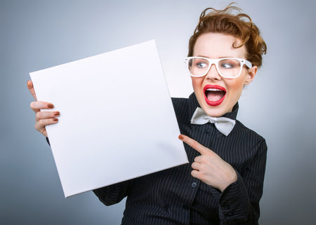 Surprised formal woman holding white empty boardの写真素材