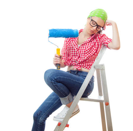 Sleepy woman with paint roller, isolated on white. Lazy female worker on renovation or wall paintingの写真素材