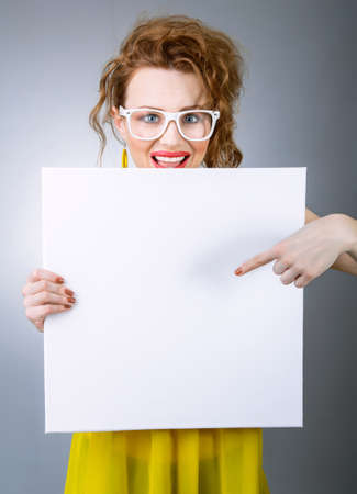 Surprised woman holding white board. Funny gilr with blank panelの写真素材