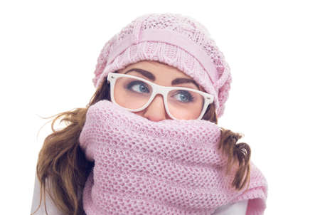 Freezing young woman hiding behind her scarf or winter clothing, isolated on white. Close up studio shotの写真素材