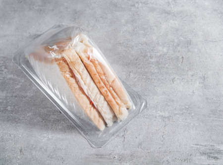 Sandwich in a transparent plastic box or nylon bag to go on gray backgroundの写真素材