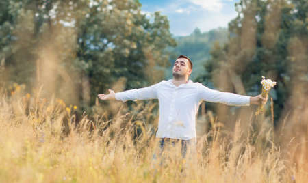 Man standing in big grass with raised arms. Freedom - wellbeing concept. Outdoorsの写真素材