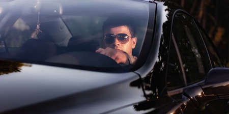 Successfull businessman in the car driving, sunset - sundown