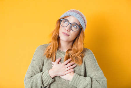 Pleased grateful beautiful young woman looking up, isolated on yellow background. Studio shotの写真素材