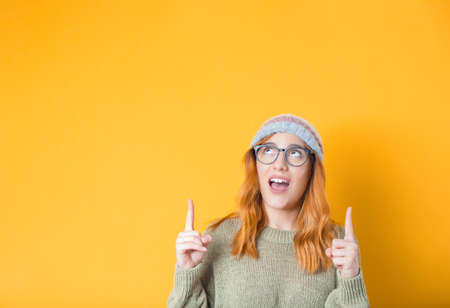 Close up beautiful young woman looking up and pointing to shows your space for product, isolated on...