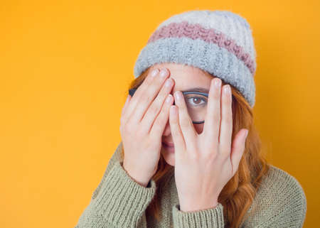 Shame. Close up young woman covering face with hands, isolated on yellow background. Oops. Ashamed girl. Studio shotの写真素材